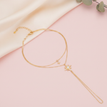 layered gold hand chain bracelet with a starburst charm and a small dangling star, shown on cream fabric with eucalyptus leaves