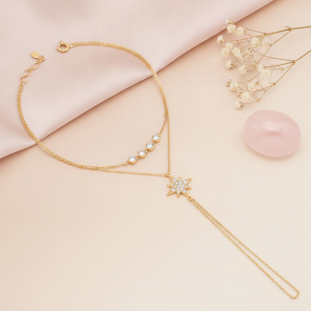 layered gold hand chain bracelet with a stone-paved starburst and a draped wrist strand, shown on cream fabric with baby's breath and a rose quartz stone