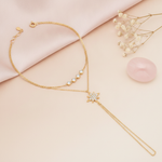 layered gold hand chain bracelet with a stone-paved starburst and a draped wrist strand, shown on cream fabric with baby's breath and a rose quartz stone