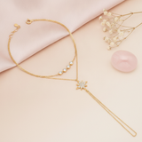 layered gold hand chain bracelet with a stone-paved starburst and a draped wrist strand, shown on cream fabric with baby's breath and a rose quartz stone