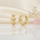 gold multi-strand arc huggie hoop earrings on a cream satin background with dried baby's breath and a rose quartz stone