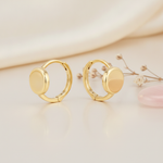 solid gold huggie hoop earrings with a smooth polished disk front on a beige background with dried baby's breath