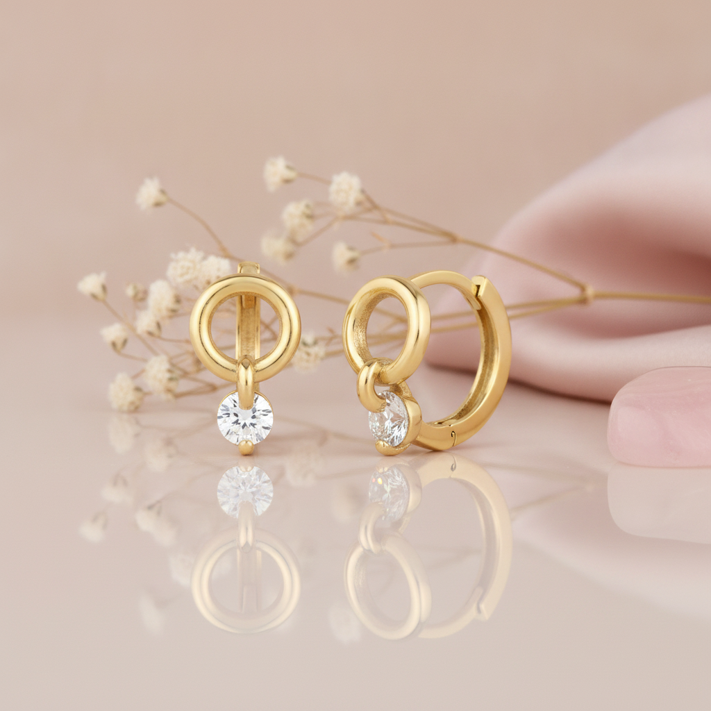 gold huggie hoop earrings with an open circle and a suspended round White CZ stone drop on a blush background with dried baby's breath