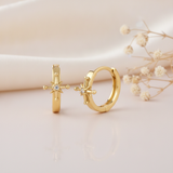 gold huggie hoop earrings with a sculpted starburst and a single White CZ stone on a cream satin background with dried baby's breath