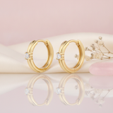 polished gold huggie hoop earrings with a single round White CZ stone on a blush background with dried baby's breath