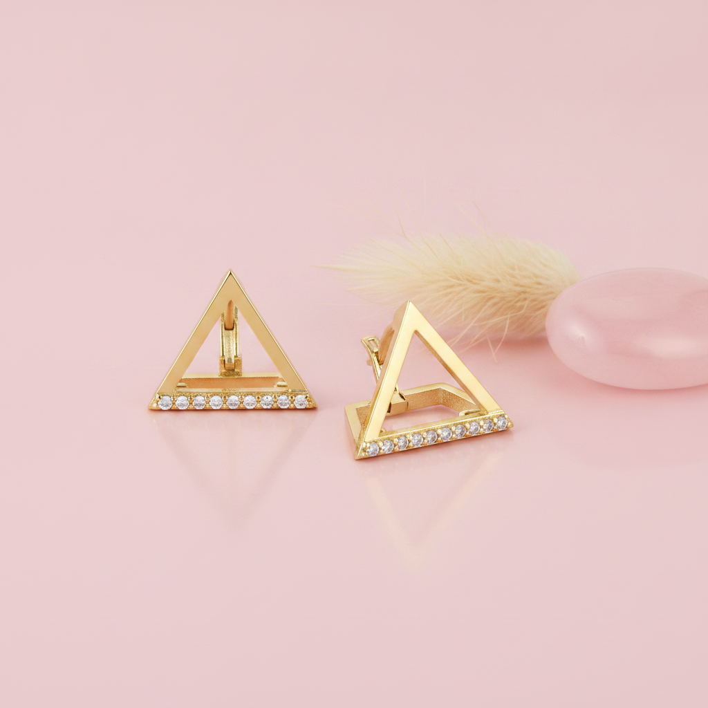 gold open-triangle huggie hoop earrings with a row of White CZ stones on a blush background with a dried flower and a rose quartz stone