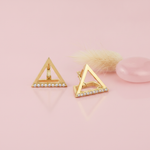 gold open-triangle huggie hoop earrings with a row of White CZ stones on a blush background with a dried flower and a rose quartz stone