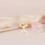 gold chevron stud earring with four round White CZ stones on a pink background with dried wheat and a rose quartz stone