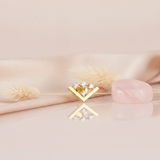 gold chevron stud earring with four round White CZ stones on a pink background with dried wheat and a rose quartz stone