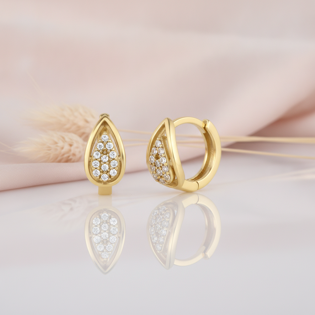 gold teardrop huggie hoop earrings paved with White CZ stones on a blush background with dried wheat sprigs