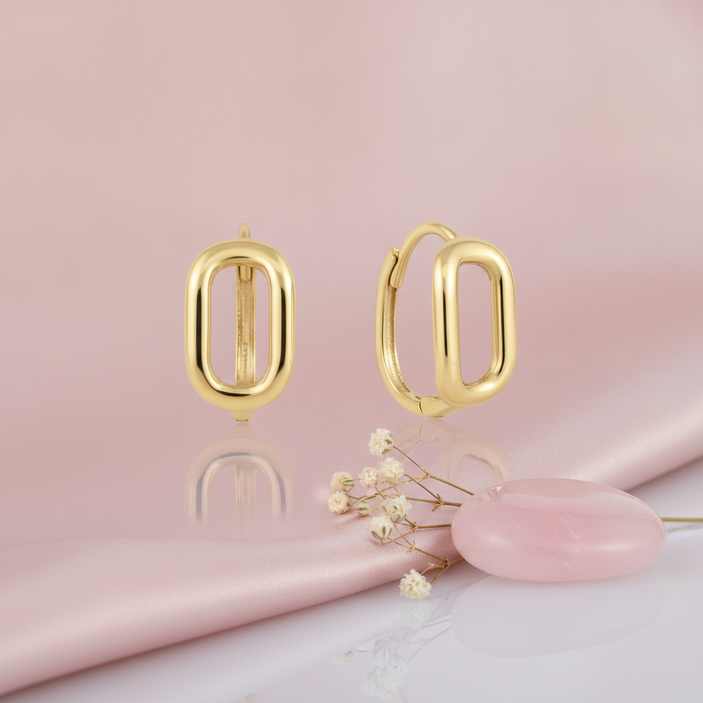 polished gold open oval hoop earrings on a pink satin background with dried baby's breath and a rose quartz stone