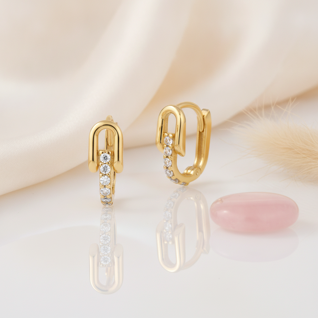 gold arched huggie hoop earrings with a track of round White CZ stones on a cream satin background with dried baby's breath