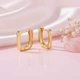 polished yellow gold soft rectangular hoop earrings on a pink background with dried baby's breath and a rose quartz stone