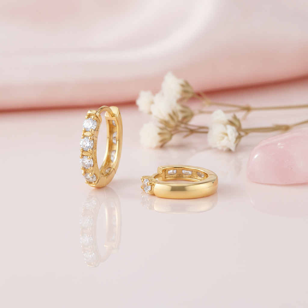 gold huggie hoop earrings with four round White CZ stones on a pink background with dried baby's breath and a rose quartz stone