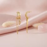 gold triple-band ear cuff earrings with pave and scattered White CZ stones, a draped chain, and a spike drop on a pink background with dried bunny tail grass