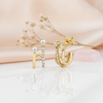 gold double-arch earrings with round and pave-set White CZ stones on a blush background with dried baby's breath and a rose quartz stone