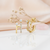 gold double-arch earrings with round and pave-set White CZ stones on a blush background with dried baby's breath and a rose quartz stone