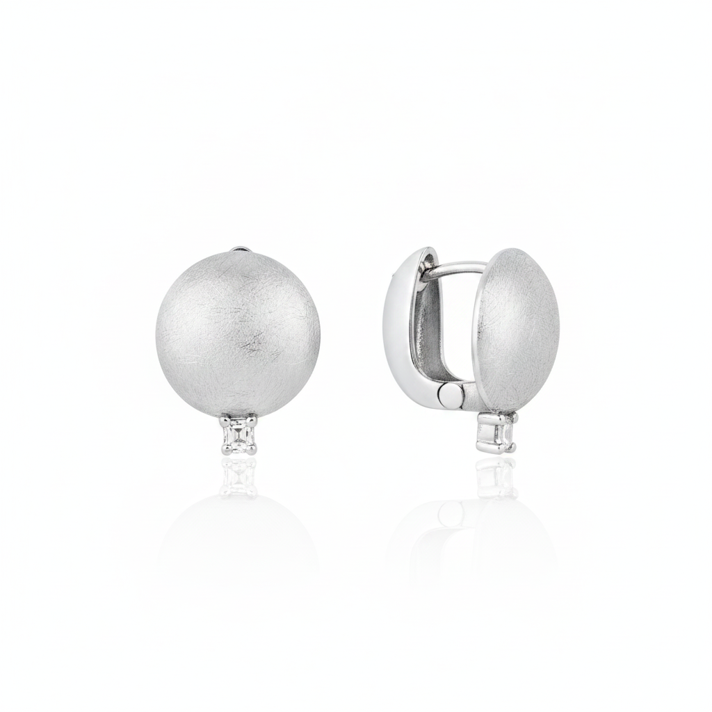 white gold brushed disc huggie hoop earrings with a single clear stone on white background