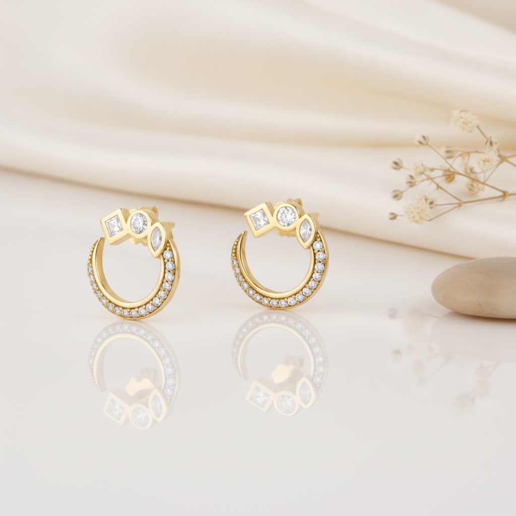 open gold hoop stud earrings topped with square, round, and marquise clear stones, styled on an ivory background with draped silk and dried flowers