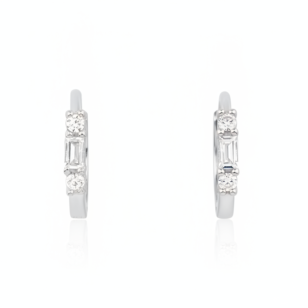 white gold huggie hoop earrings with a baguette-cut and round clear stones on white background