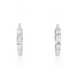 white gold huggie hoop earrings with a baguette-cut and round clear stones on white background
