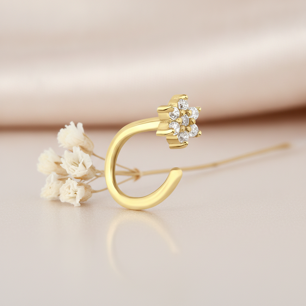 gold open hoop earring with a floral cluster of clear stones, styled with a dried flower on a blush background