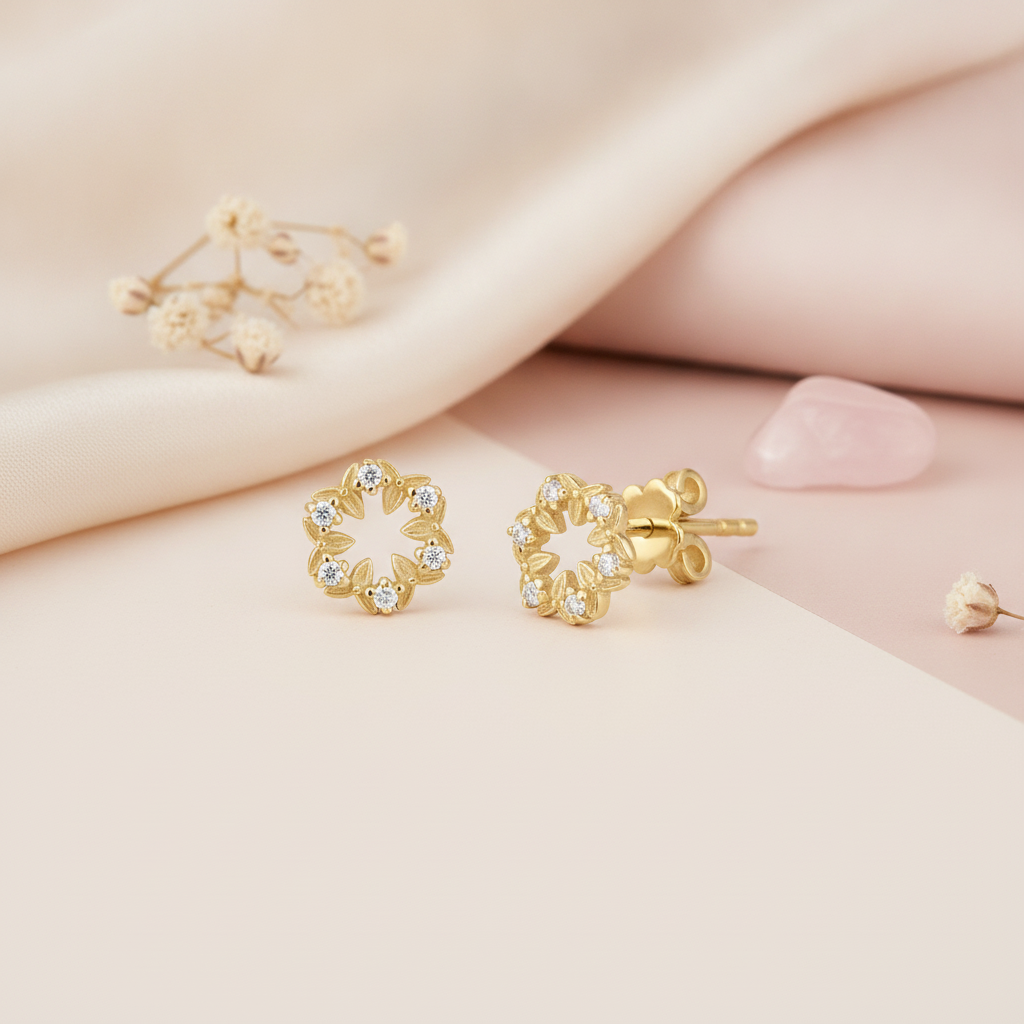 gold leaf wreath stud earrings with six clear stones, styled on a two-tone pink and cream background with dried flowers and a pink stone
