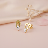 open gold loop stud earrings with a pear-cut clear stone drop, styled on a pink background with draped silk and dried flowers