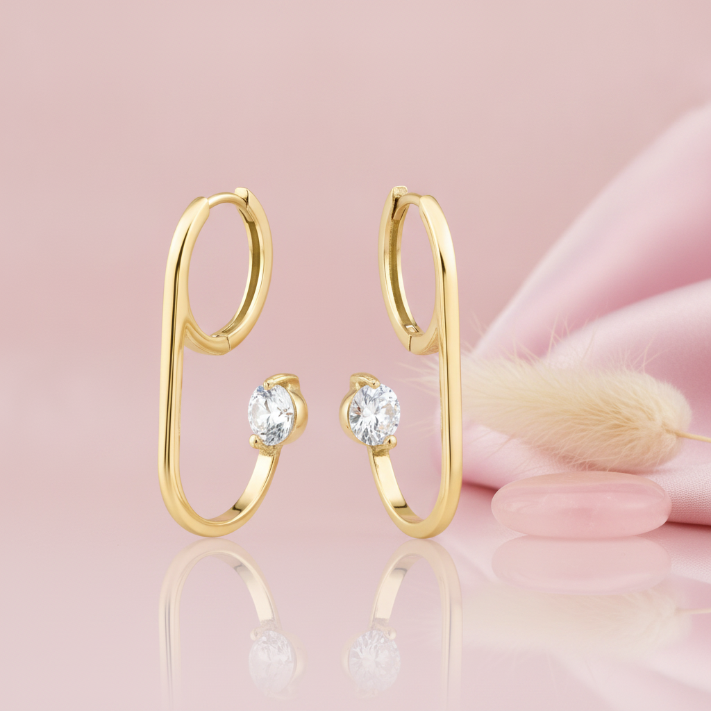 gold open loop hoop earring with a single floating round stone, styled with a feather and a pink stone on a pink background
