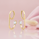 gold open loop hoop earring with a single floating round stone, styled with a feather and a pink stone on a pink background