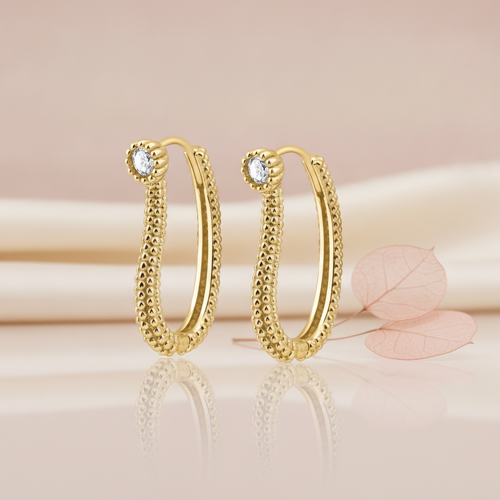 gold beaded oval hoop earrings with a White CZ stone accent, styled with a dried leaf on a blush background
