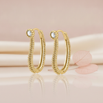 gold beaded oval hoop earrings with a White CZ stone accent, styled with a dried leaf on a blush background
