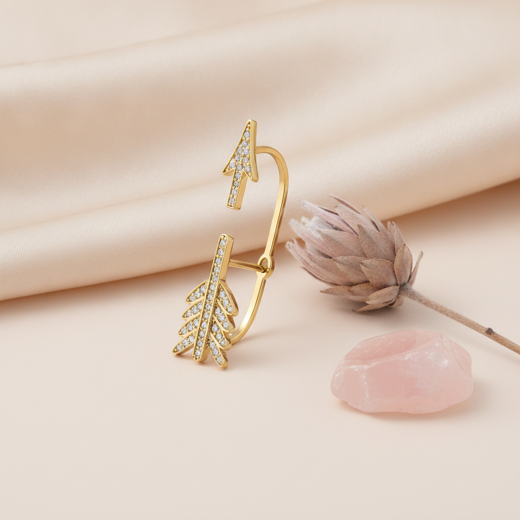 gold split arrow ear cuff earring with pave White CZ stones, styled with a dried flower and a pink stone on a cream background