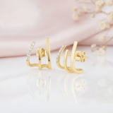 gold triple bar ear cuff earrings with one row of White CZ stones, styled with dried flowers on a blush background