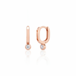 rose gold oval huggie earrings with a bezel-set clear stone on white background