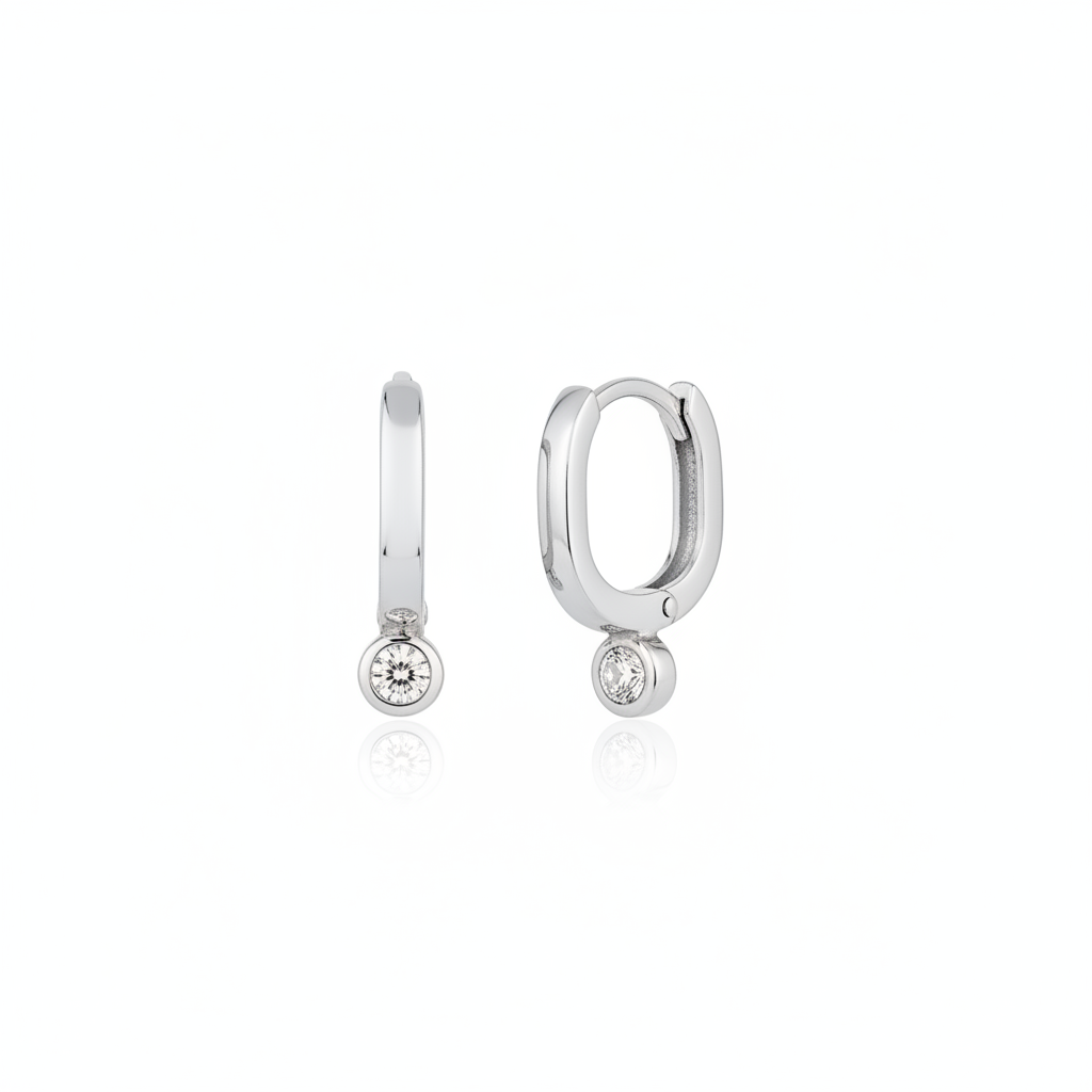white gold oval huggie earrings with a bezel-set clear stone on white background