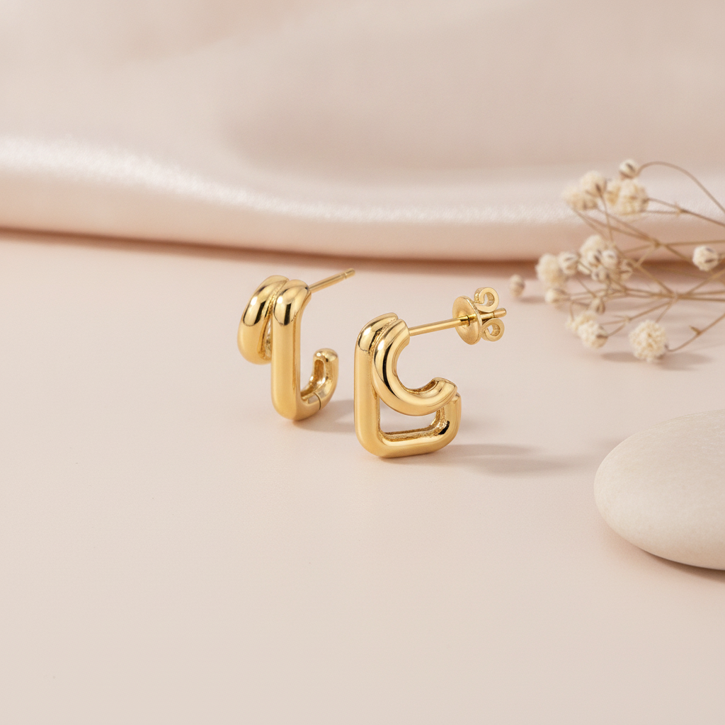 gold double arch stud earrings styled with dried baby's breath flowers on a blush background