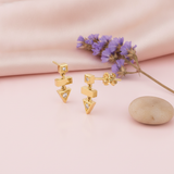 gold geometric drop earrings with stacked square, bar and triangle shapes set with clear stones, styled with purple flowers on a pink background