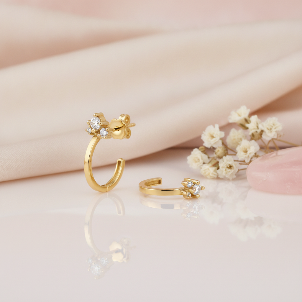 gold open hoop earrings topped with a cluster of clear stones, styled with dried baby's breath on a blush background