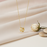 gold barrel pendant necklace styled with a dried white rose on a cream background