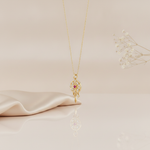 gold talisman wheel necklace with a pink center stone styled with dried flowers on a cream background