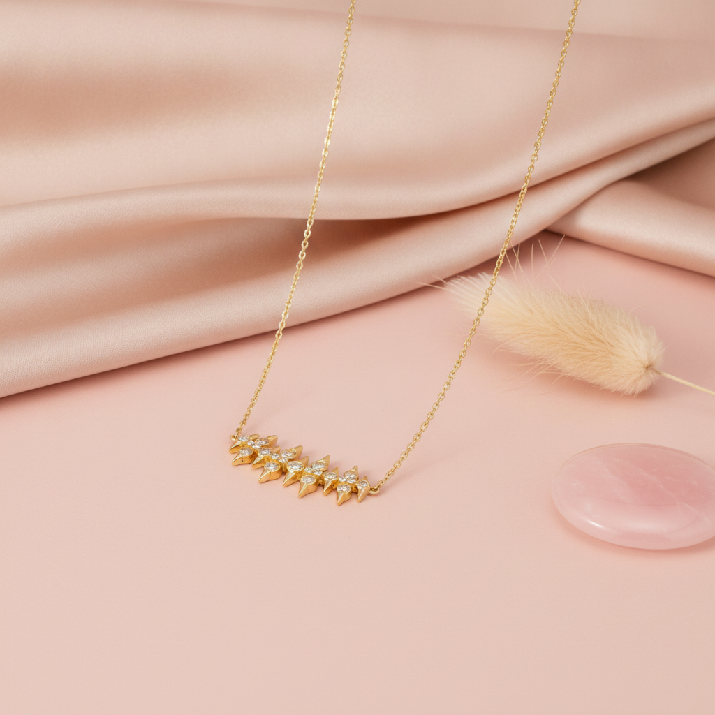 gold spike bar necklace styled with a dried rose and eucalyptus on a blush background