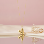 gold tilted heart pendant necklace styled with dried baby's breath on a blush background
