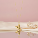 gold tilted heart pendant necklace styled with dried baby's breath on a blush background