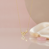 gold starburst pendant necklace styled with a fuzzy pink stem and a pink stone on a blush background