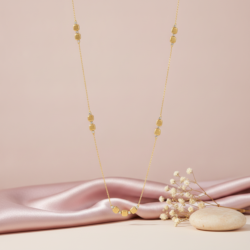 gold square station necklace styled with dried baby's breath on a cream background