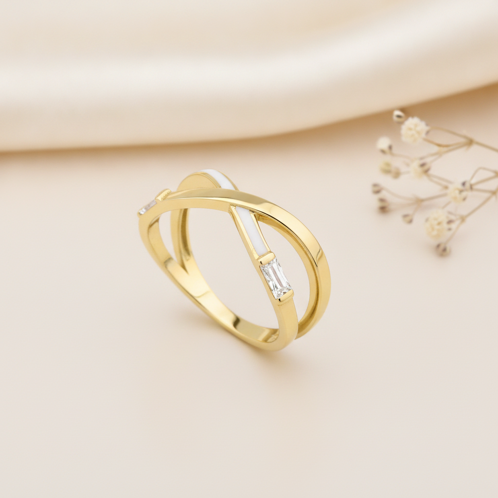 gold crossover ring with white enamel and a baguette stone styled with dried flowers on a cream background