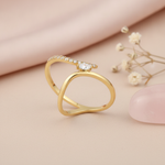 gold bypass ring with a marquise stone styled with dried flowers on a blush background