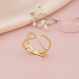 gold open arc ring with pave stones styled with a pink stone on a blush background