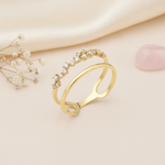 gold double band ring with clustered stones styled with dried flowers on a blush background